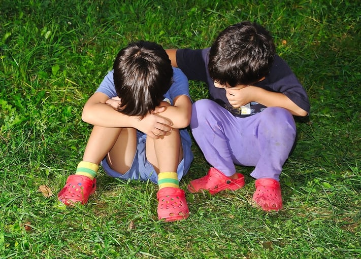 Two cute children sitting on ground, consoling each other.jpeg